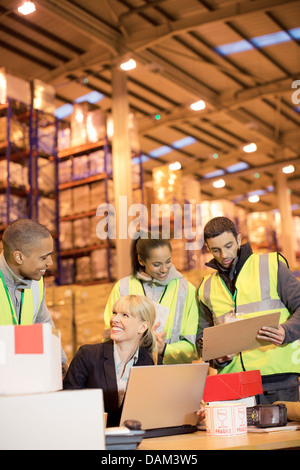 Geschäftsfrau und Arbeitnehmer sprechen im Lager Stockfoto