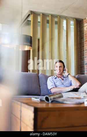 Mann, zuhören, Kopfhörer auf sofa Stockfoto