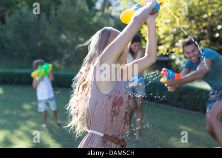 Familie spielt mit Wasserpistolen in Hinterhof Stockfoto