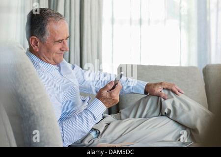 Älterer Mann mit Handy auf sofa Stockfoto