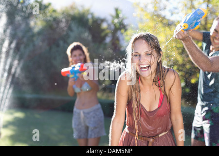 Freunde spielen mit Wasserpistolen in Hinterhof Stockfoto