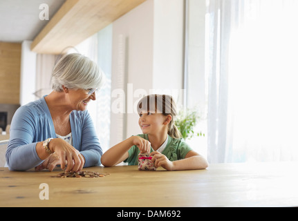 Ältere Frau und Enkelin Füllung ändern Glas Stockfoto