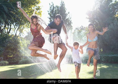 Familie in Sprinkler springen Stockfoto