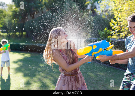 Paar mit Wasserpistolen in Hinterhof spielen Stockfoto