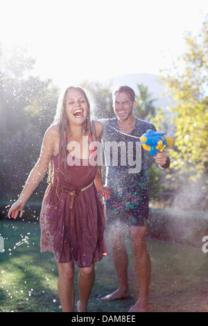 Paar mit Wasserpistolen in Hinterhof spielen Stockfoto