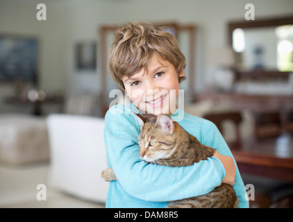 Junge umarmt Katze im Wohnzimmer Stockfoto