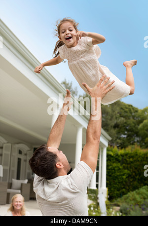 Vater und Tochter spielen vor Haus Stockfoto