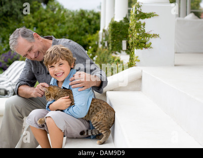 Älterer Mann und Enkel Petting Katze auf Schritte Stockfoto