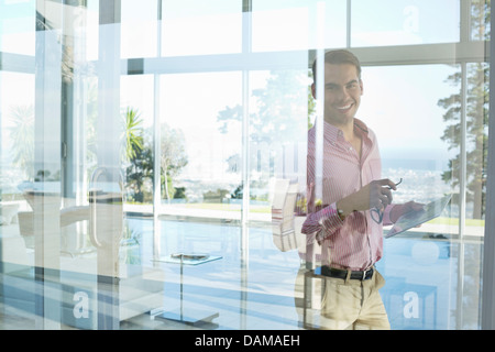 Geschäftsmann lächelnd an Bürofenster Stockfoto