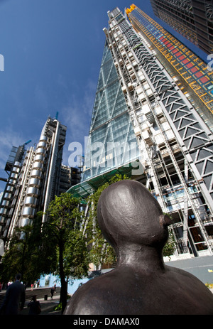 Detail der Skulptur von Anthony Gormley in Stadt von London mit Lloyds Building und "Cheesegrater" hinter Stockfoto