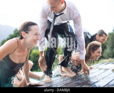 Vollständig bekleidet Freunde klettern aus Schwimmbad Stockfoto