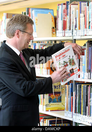 Bundespräsident Christian Wulff nimmt ein Buch aus dem Regal bei der Wiedereröffnung der Deutschlands größte Kinder Bibliothek in der Mittel- und staatliche Bibliothek (ZLB) in Berlin, Deutschland, 6. Juni 2011. Foto: WOLFGANG KUMM Stockfoto