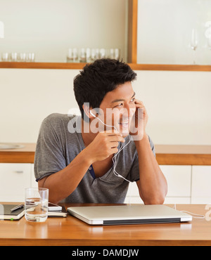 Mann trägt Kopfhörer am Tisch Stockfoto