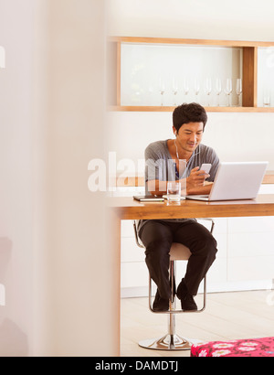 Mann mit Handy und Laptop am Tisch Stockfoto