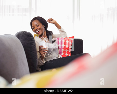 Frau, zuhören, Kopfhörer auf sofa Stockfoto