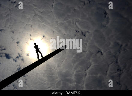 Die Sonne scheint durch ein Loch in den Wolken hinter der Skulptur "Man walking to the Sky" des US-amerikanischen Künstlers Jonathan Borowsky in Kassel, Deutschland, 10. Juni 2011. Foto: Uwe Zucchi Stockfoto