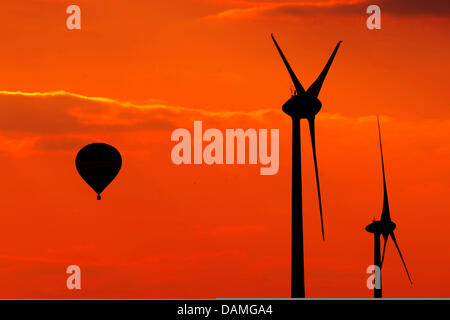 (DATEI) Eine Archivfoto vom 17. April 2011 zeigt einen Heißluft-Ballon schwebt vorbei an Windkraftanlagen bei Sonnenuntergang in Tiefenthal, Deutschland. Am 6. Juni 2011 entscheidet das Kabinett über einen umfassenden nuklearen und Energiepaket mit zahlreichen Änderungen an dem Gesetz. Foto: Marius Becker Stockfoto