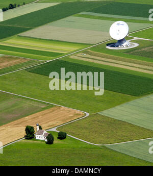 Die Wallfahrtskapelle St. Johann steht neben einem großen Parabolantenne der Erde Station in der Nähe von Raisting, Deutschland, 21. Juni 2011. Foto: Peter Kneffel Stockfoto