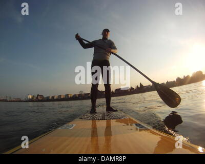 Deutsch Surfen Paddler, die Olaf Schwarz auf seinem Surfbrett steht, wie er am Rhein in der Nähe von Bonn, Germany, 1. Februar 2011 Paddel. Im Gegensatz zu konventionellen offenen Wasser mit starker Strömung und die "perfekte" Welle surfen ist Surfen, Paddeln eine Sportart, die erfordert Koordination, Kraft und Ausdauer und erfolgt in der Regel auf Seen und Flüssen. Foto: Olaf Schwarz Stockfoto