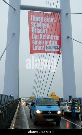 Ein Banner von politische Partei "Die Linke" (die linke) hängt auf Rügen-Brücke in Stralsund, Deutschland, 4. Juli 2011. Die Partei ist protestieren gegen niedrige Löhne im Hotel-und Gastgewerbe in Norddeutschland zu Beginn der Urlaubssaison. Die Brücke verbindet die Insel Rügen mit Festland Deutschland. Foto: Stefan Sauer Stockfoto