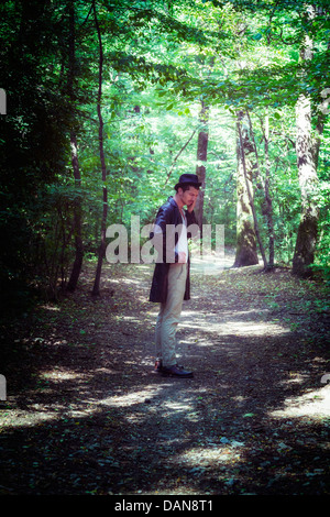 erschöpften Mann mit schwarzer Jacke und Hut im Wald Stockfoto