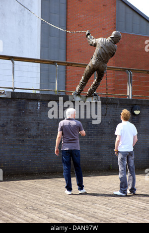 Männer auf der Suche an der Statue zum Gedenken an die Schiffbau-Geschichte des Clyde bei Braehead in Glasgow. Stockfoto