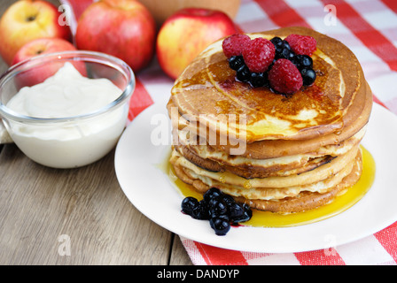 Stapel von Pfannkuchen mit Beeren in die weiße Platte auf dem Holztisch Stockfoto