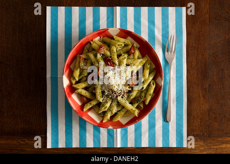 Pasta mit Pesto-Sauce mit Petersilie, Parmesan-Käse und Tomaten auf "Gingham" Teller Türkis Serviette und Gabel auf rustikale Eichentisch Stockfoto