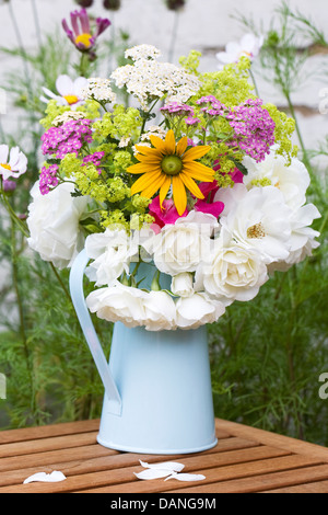 Achillea, Rudbeckia, Alchemilla, Rosen und Wicken in einem blassen blauen Krug. Stockfoto