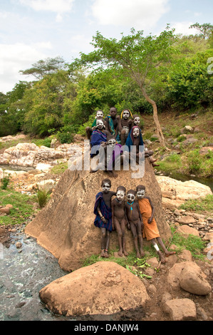 Suri (Surma) Kinder mit aufgemalten Gesichtern auf einem Felsen, Äthiopien Stockfoto