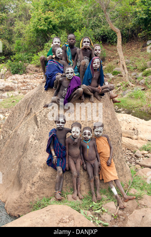 Suri (Surma) Kinder mit aufgemalten Gesichtern auf einem Felsen, Äthiopien Stockfoto