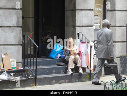 Eine alte Frau verkauft einige ihrer persönlichen Gegenstände am Eingang zu ihrem Haus auf der 49th Street, Manhattan, New York, USA, 13. Juli 2011. US-Präsident Barack Obama ringt mit Kongreßführer über ein Abkommen über die Schulden des Landes. Wenn das Problem nicht bis 2. August 2011 gelöst ist, ist es nicht garantiert, dass eine geschätzte 50 Millionen Rentner, pensionierte militärische Personne überprüft Stockfoto