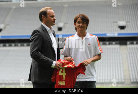 Sportdirektor Christian Nerlinger (L) des Fußball-Bundesligisten FC Bayern München posiert mit japanischer Fußballspieler Takashi Usami und der New-Jersey der letzteren in der Allianz Arena in München, Deutschland, 18. Juli 2011. Der 19-Year-Old-Spieler ist auf Leihbasis für ein Jahr. Foto: Andreas Gebert Stockfoto