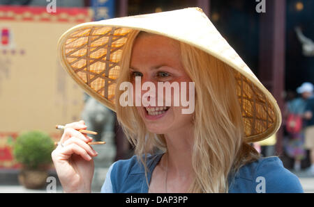 Deutsche Schwimmerin Britta Steffen ist ein chinesischer Hut mit Stäbchen während eines Besuchs für einen Bericht von der ARD-Sportschau in der Yu-Garten vor den FINA Schwimmweltmeisterschaften 2011 in Shanghai, China, 18. Juli 2011 gesehen. Foto: Bernd Thissen dpa Stockfoto