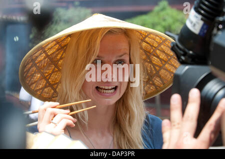 Deutsche Schwimmerin Britta Steffen ist ein chinesischer Hut mit Stäbchen während eines Besuchs für einen Bericht von der ARD-Sportschau in der Yu-Garten vor den FINA Schwimmweltmeisterschaften 2011 in Shanghai, China, 18. Juli 2011 gesehen. Foto: Bernd Thissen dpa Stockfoto