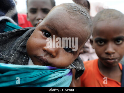 Fliegen in den Augen der somalisch-Flüchtling-Baby Robay, kriechen, wie seine Mutter ihr trägt vier Monate altes jüngste durch ein Flüchtlingslager in Dadaab, Nordosten Kenias auf Dienstag, 2. August 2011. Somalia und Kenia getroffen haben in sechs Jahrzehnten von einer der schlimmsten Dürren und Hungersnöte, über 350,000 Flüchtlinge Unterschlupf gefunden haben, in der weltweit größten Flüchtlingslager. Foto: Boris R Stockfoto