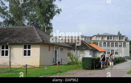 Die Menschen gehen vorbei an Wohnungen von der ehemaligen Olympischen Dorf Elstal, Deutschland, 3. August 2011. 4066 Athleten aus 46 Nationen lebte im Dorf für die Olympischen Sommerspiele, die 1936 in Berlin stattfand. Das Dorf wurde in ein Museum umgewandelt und ist seit 6. August 2011 für die Öffentlichkeit zugänglich. Die Ausstellung "Zwei Seiten einer Medaille" entstand durch die Stiftung Deutsche Kreditbank DKB (G Stockfoto