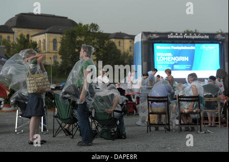 Wagner-Fans trotzen der plötzliche Wolkenbruch mit Regenponchos und Sonnenschirmen während das public viewing von Wagners Oper "Lohengrin" auf dem Volksfestplatz (Folk Festival Square) in Bayreuth, Deutschland, 14. August 2011. Oben wurden zu 40 000 Besucher auf dem Festival an diesem Tag erwartet. Foto: David Ebener Stockfoto