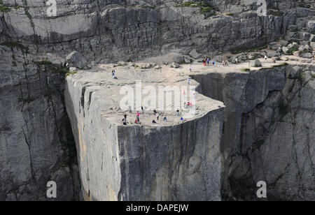 Besucher zu Fuß entlang der so genannten Preikestolen Steilküste auf den Lysefjord in der Nähe von Stavanger, Norwegen, 4. August 2011. Der Rand der Klippe fällt mehr als 600 Meter senkrecht nach unten in den 40 Kilometer langen Fjord. Das Plateau ist ein beliebtes Ziel für Wanderer und seine besuchten Tausende von Touristen jedes Jahr. Foto: Rainer Jensen Stockfoto