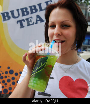 Eine junge Frau hält eine Tasse des neuesten Kultgetränk Bubble Tea oder Bubble Milk Tea im "Tee & Café BoboQ" Store am Alexanderplatz in Berlin, Deutschland, 17. August 2011. Das Geheimnis um die ursprünglich asiatische Mischung aus grünen oder schwarzen Tee mit Milch oder Joghurt und Obst Sirup sind die unterschiedlich aromatisierten Luftblasen aus Stärke gewonnen. Bereits in den USA sehr beliebt, Bubble Tea findet mehr ein Stockfoto