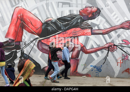 Fußgänger zu Fuß vorbei an Straßenkunst Graffiti Wandmalerei in La Candelaria Barrio von Bogota, Kolumbien. Stockfoto