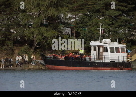 Überlebende der Utoya Massaker und ihre Verwandten kommen auf einem Schiff auf der Insel Utoya, Norwegen, 20. August 2011. Vier Wochen nach der Bombenexplosion in Oslo und dem folgenden Massaker in einem Ferienlager auf der Insel Utoya Norwegen erinnert an die 77 Opfer des Angriffs mit einer dreitägigen Trauerfeier. Foto: Hannibal Hanschke Stockfoto