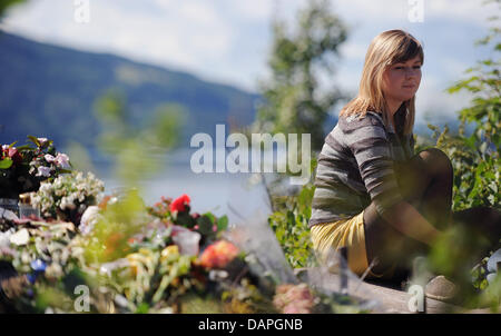 Eine Überlebende des Massakers sitzt auf einer Website über wo Blumen gegenüber den Fjord liegen Insel Utoya, Norwegen, 20. August 2011. Vier Wochen nach der Bombenexplosion in Oslo und das Massaker in Ferienlager auf der Insel Fjord hält Norwegen eine dreitägige Gedenkfeier für die 77 Toten. Foto: Hannibal Stockfoto