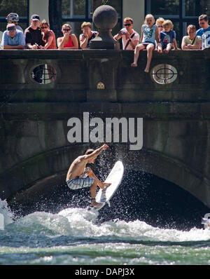 Ein junger Mann auf seinem Surfbrett springt über die "Eisbach-Welle" am Fluss Eisbach im englischen Garten in München, 23. August 2011. Passanten beobachten die Surfer von der Brücke. Die Eisbach-Welle bei Prinzregenten Street ist ein berühmter Ort für Surfer und Wassersportler das ganze Jahr. Foto: Peter Kneffel Stockfoto