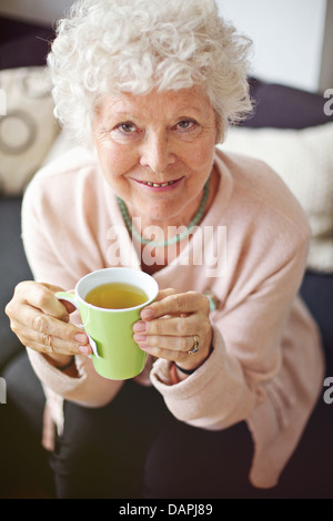 Indoor senior Frau genießen ihren Tee und Lächeln Sie Stockfoto