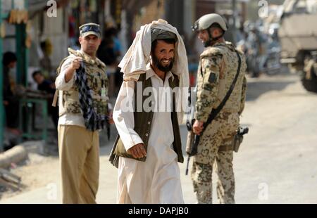 Ein afghanischer Mann herein übergebenen Bundeswehr Soldat Khanabad in Kunduz, Afghanistan, 23. August 2011. Sie blockiert hatte die Website einer hausgemachten Bombe, die von unbekannten Personen auf der Straße zu den Polizeichef Haus begraben wurde entdeckt. Afghanistan-Sicherheits- und Polizeikräfte werden immer wieder von den Taliban angegriffen. Foto: MAURIZIO GAMBARINI Stockfoto