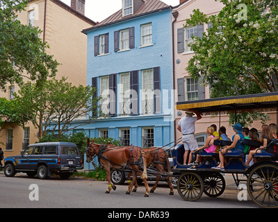 Eine Kutsche gezogen von Maultieren nimmt Touristen auf einer Tour von Rainbow Row in Charleston, South Carolina. Stockfoto