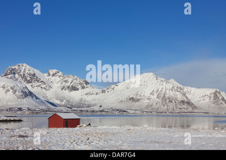 Rot isoliert Holz Rorbuer Kabine entlang der Küste in den Schnee im Winter, Lofoten-Inseln, Nordland, Norwegen, Skandinavien Stockfoto