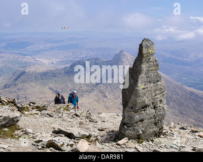 Wanderer in der Nähe von Stein Marker an Spitze der Watkin Pfad auf Snowdon Südgrat mit Y Lliwedd in Snowdon horseshoe Snowdonia Wales UK Stockfoto