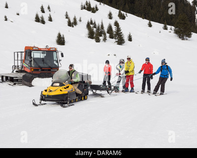 Skifahrer abgeschleppt mit dem kostenlosen Ski-Doo Motorschlitten fahren Gite du Lac de Gers Restaurant im Skigebiet Le Grand Massif. Samoëns Frankreich Stockfoto